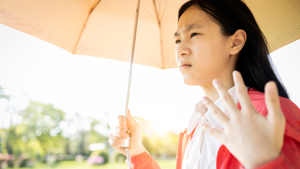 A woman holding umbrella in extreme heat for uv protection