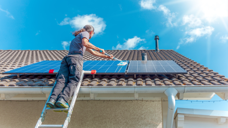 A man cleaning a solar panel installed on a residential rooftop